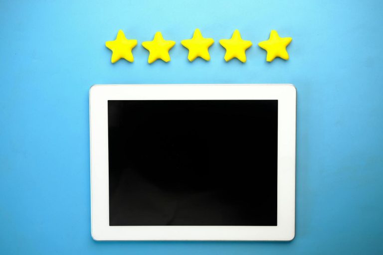 A white tablet with a blank screen on a blue background, with five yellow stars arranged in a row above it.