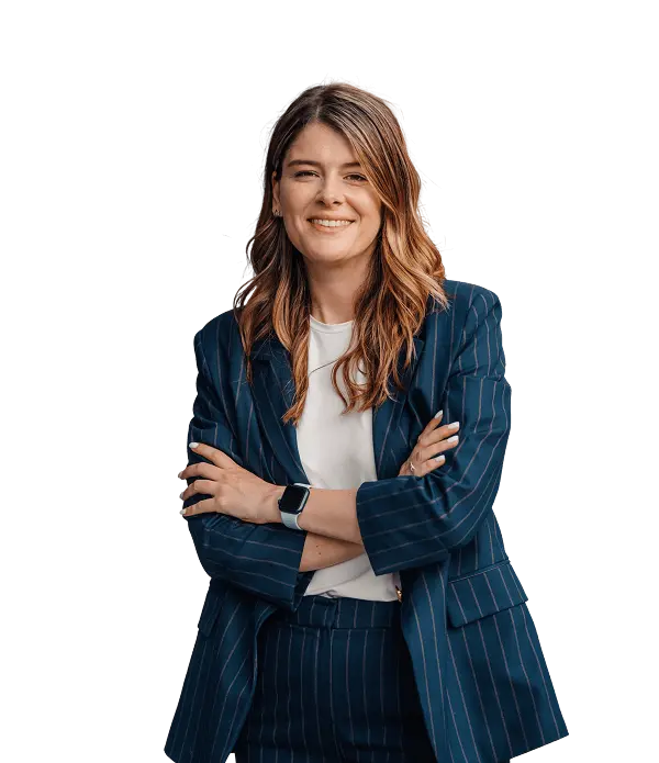 A woman wearing a blue pinstripe suit and white shirt stands with arms crossed, smiling at the camera.