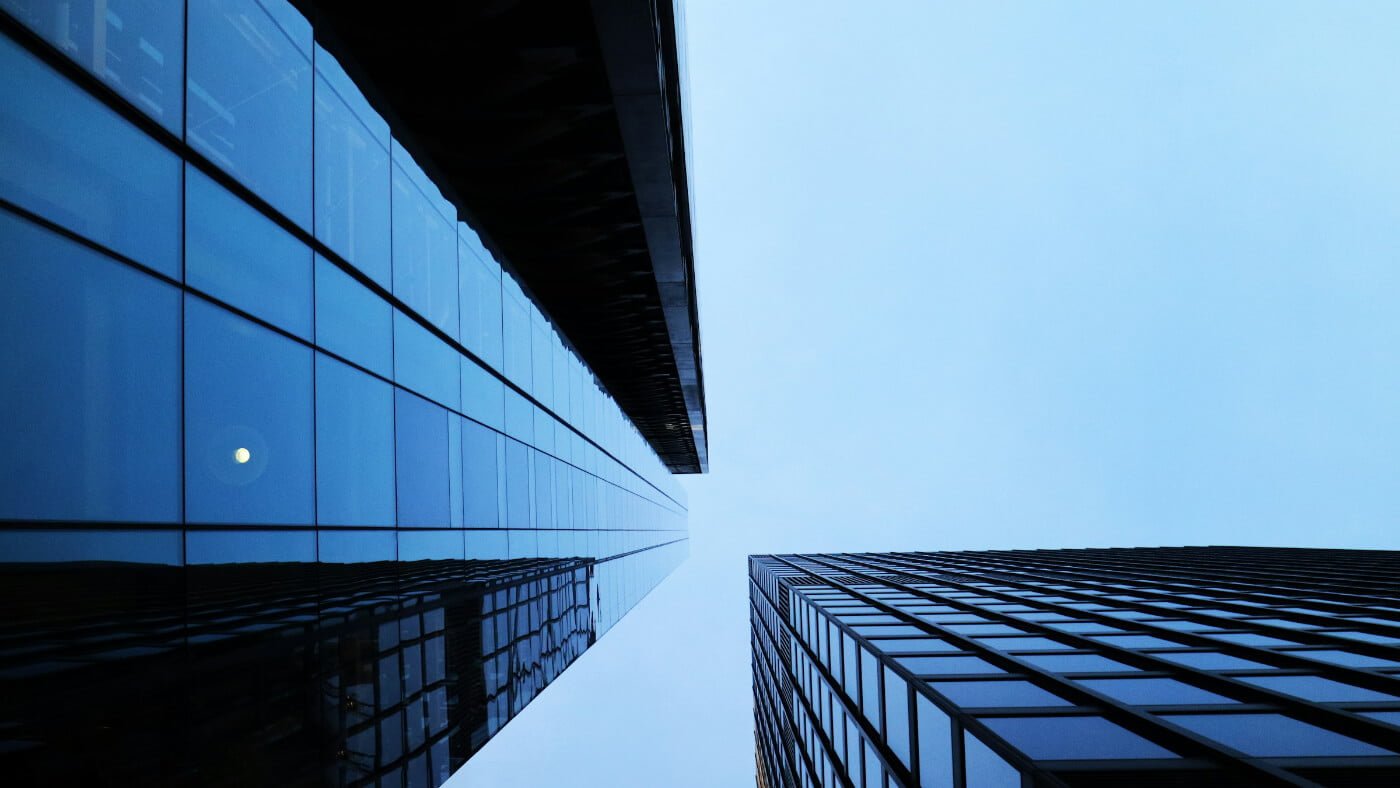 View from below of two tall skyscrapers with glass and metal facades converging into a cloudy sky, symbolizing the towering nature of privacy policy issues in modern architecture.