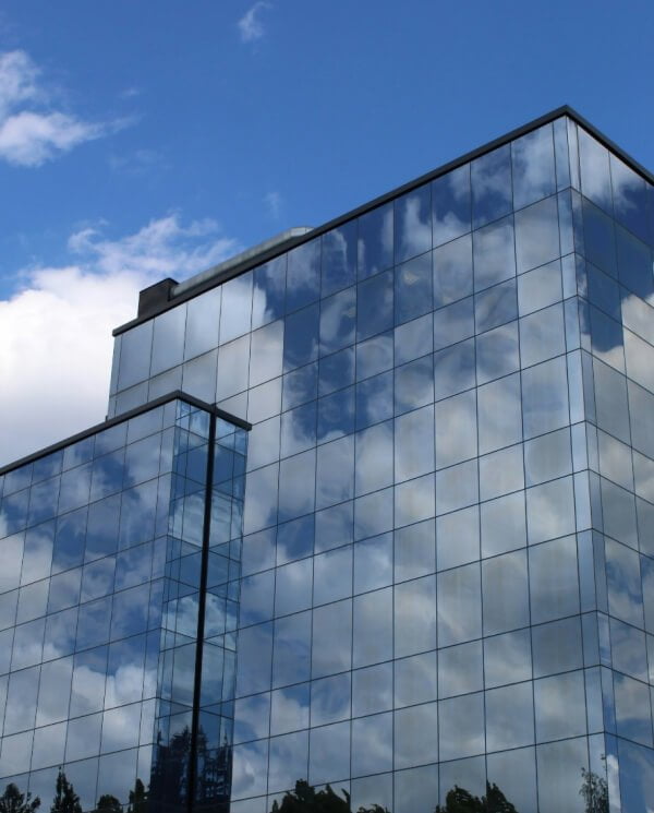 A modern glass building reflecting the blue sky and clouds.