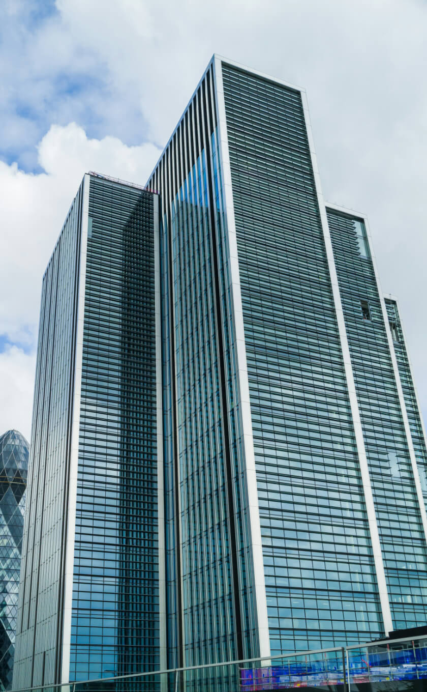 Tall modern skyscraper with glass and steel facade under a partly cloudy sky.