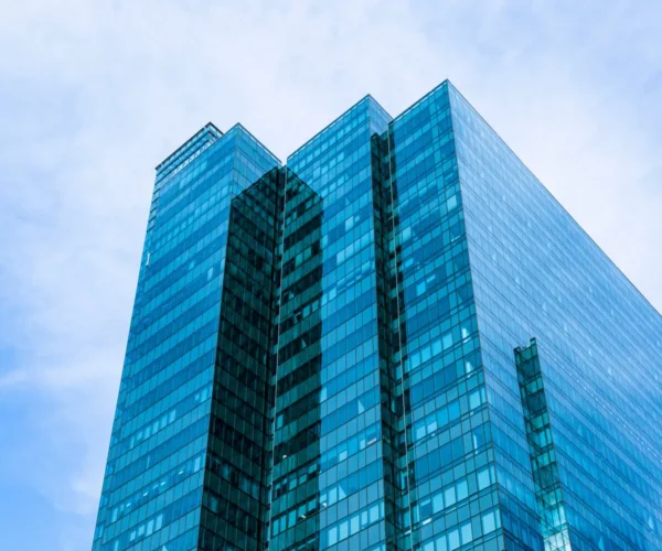 Modern glass office building against a blue sky background.