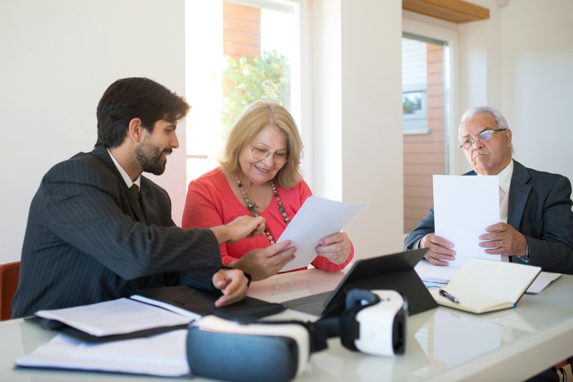 Three professionals reviewing an aged care business plan document together in a modern office setting