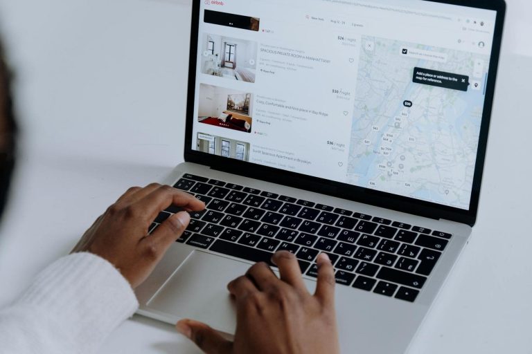 Person using a laptop to browse accommodation listings on a website, with rental details and a map visible on the screen.