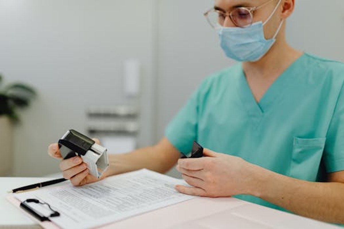 Healthcare worker reviewing patient files and compliance documentation with a stamp