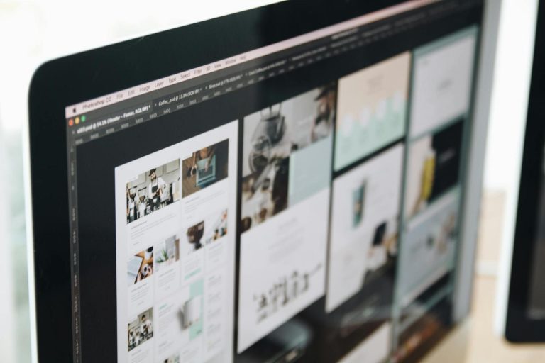 A computer monitor displays a graphic design program with multiple website layout mockups and images open on the screen.