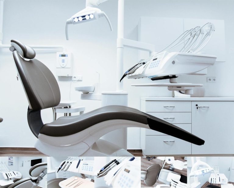 A modern dental office with an empty dental chair, overhead light, and various dental instruments in a clean, white environment.